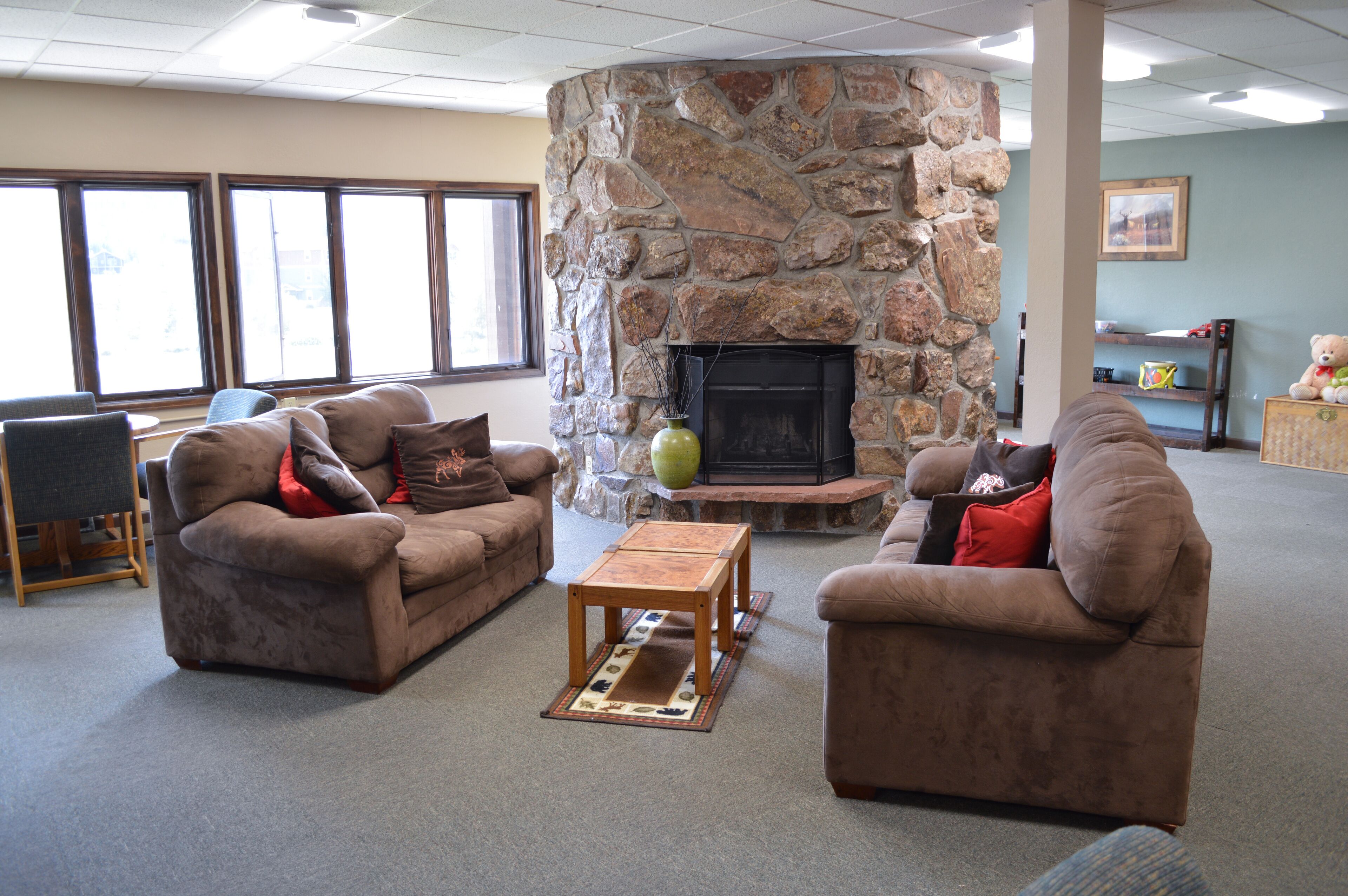 A living room with two brown sofas, a wooden coffee table, and a stone fireplace.