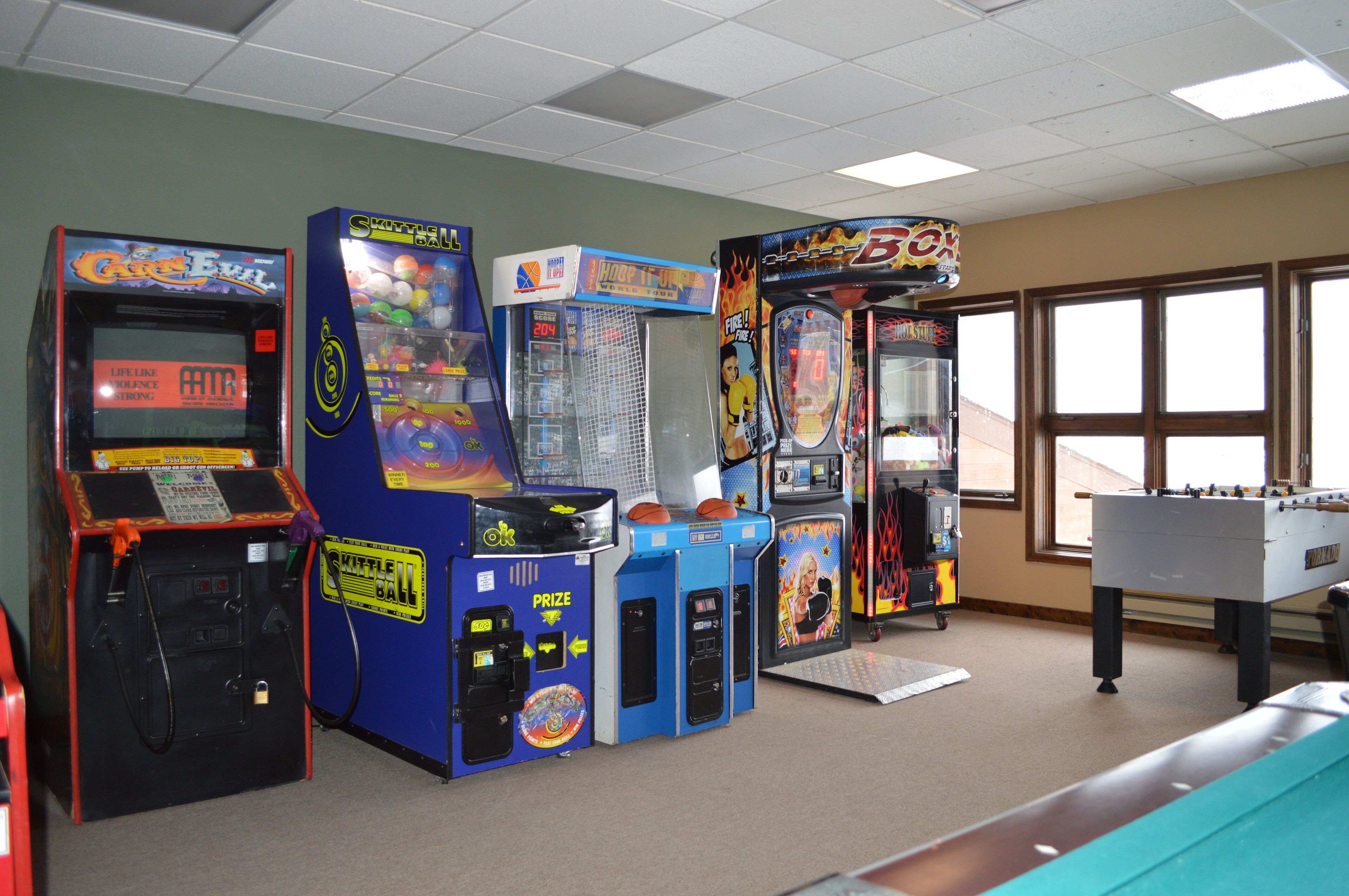 A room with various arcade games, including 'The Game of Life' and 'Skittle Ball'.
