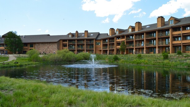 A hotel with a pond and fountain, featuring a stone facade and multiple balconies.