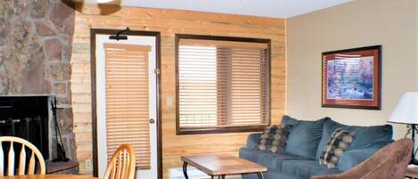 A cozy living room with a stone fireplace, wooden door, and a blue couch.