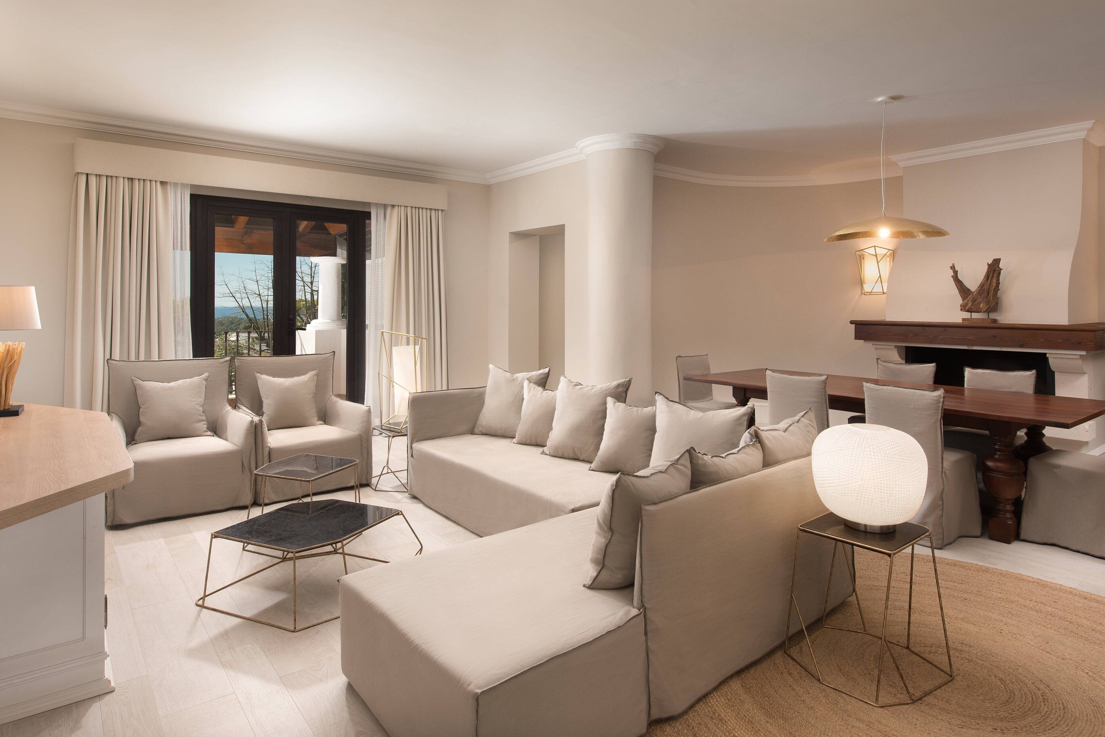 A modern living room with a sofa set, a dining table, and a view of the outdoors.
