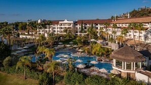 Een resort met diverse zwembaden, palmbomen en een groot gebouw met balkons.
