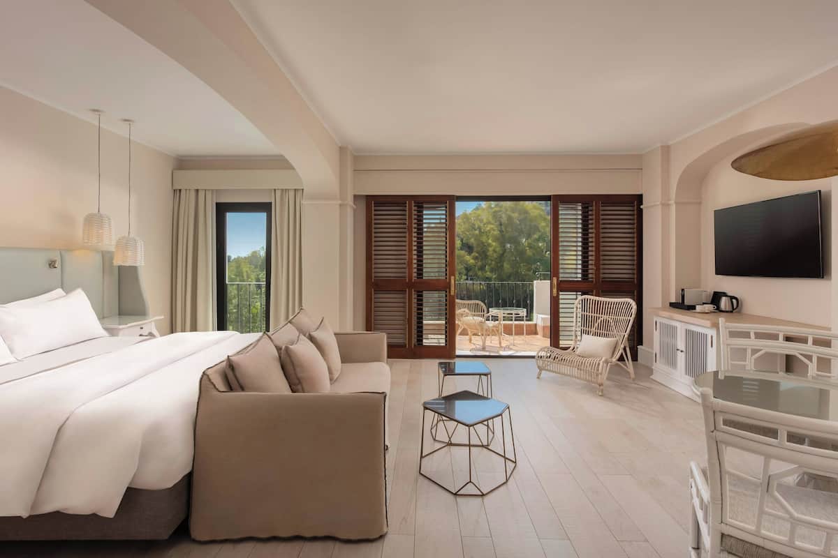 Een moderne hotelkamer met een groot bed, een sofa, een klein tafeltje en een televisie.