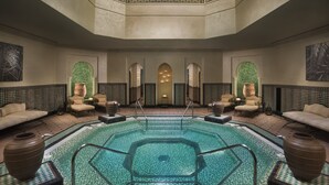 Een wellnessruimte met een centraal gelegen zwembad, zitplaatsen en een decoratief plafond.