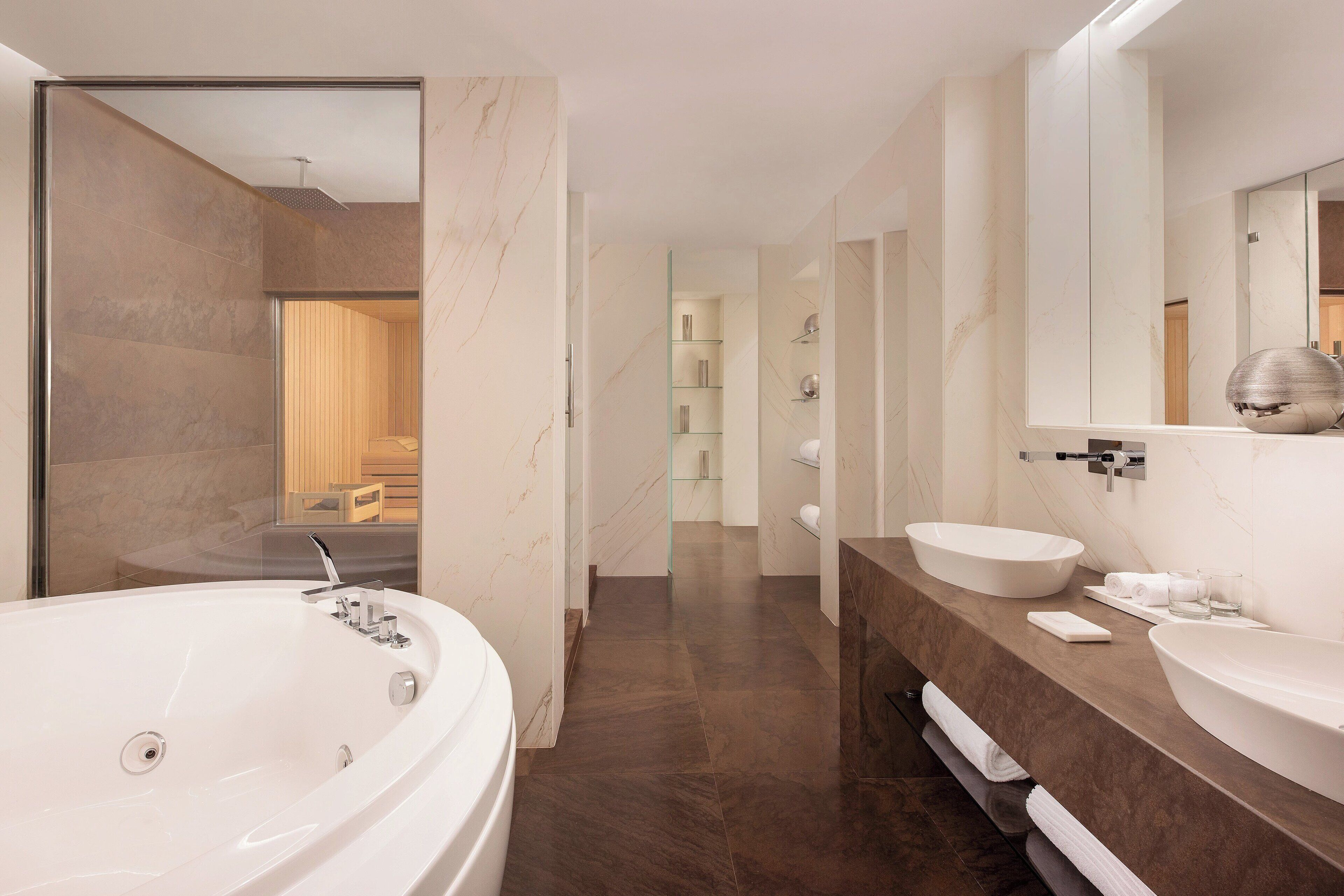 A modern bathroom with a large bathtub, two sinks, and a walk-in shower.