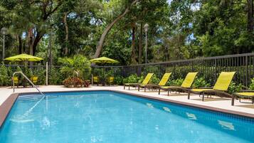 Una piscina al aire libre, sombrillas, sillones reclinables de piscina