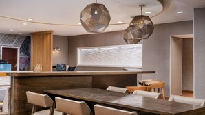 Een moderne hotellobby met een houten receptiebalie, een bar en zitplaatsen.