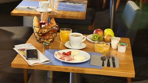 A breakfast setting with croissants, fruit, coffee, and juice on a wooden table.
