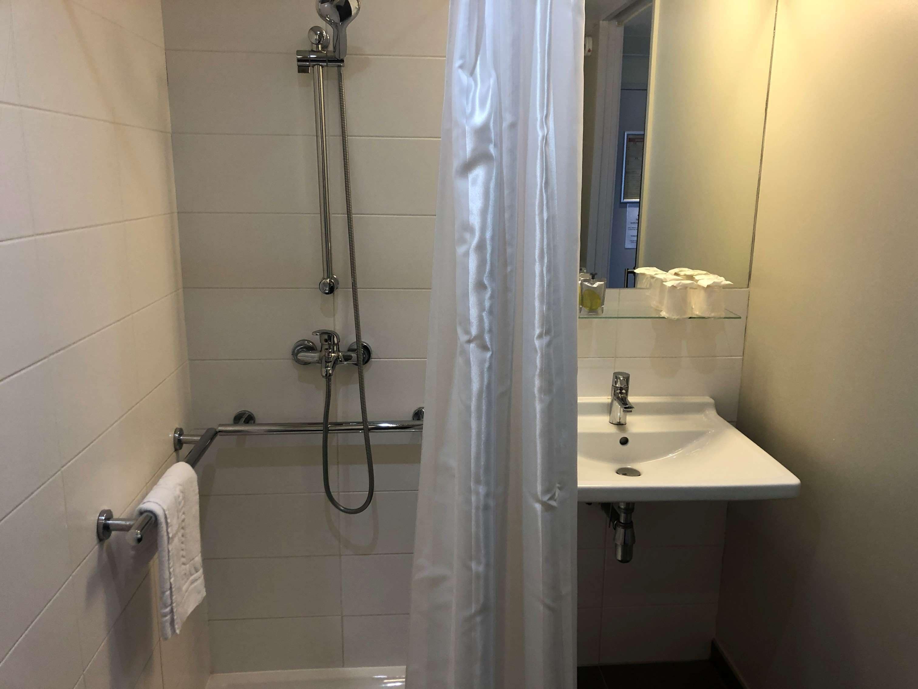 Un bagno con doccia, lavandino e specchio.