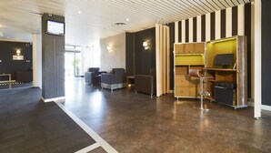 A modern lobby with a wooden ceiling, seating area, and a bar with a television.