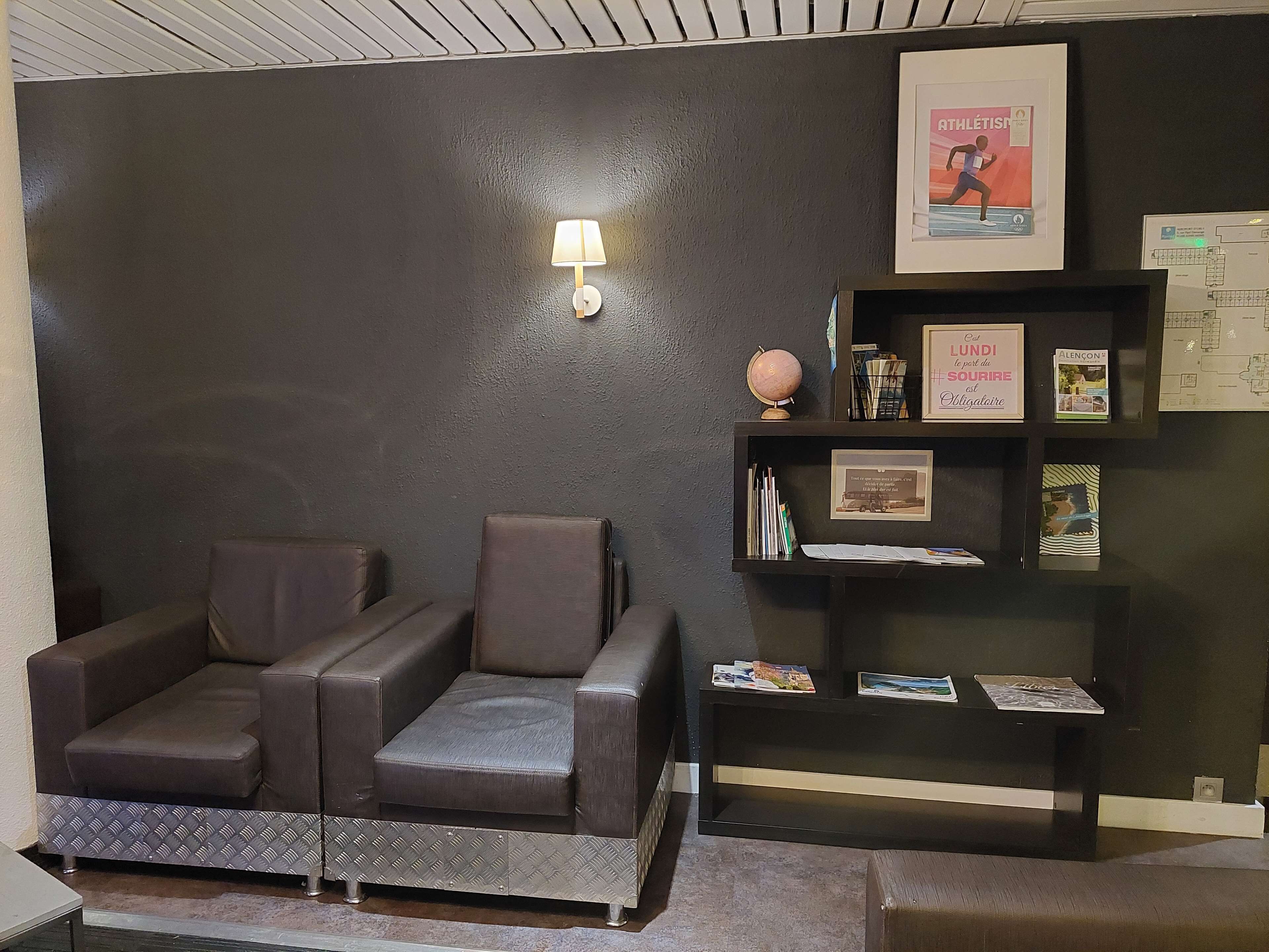 Una habitación con una pared oscura, un sofá, una mesita con un globo terráqueo y una estantería con libros y objetos enmarcados.
