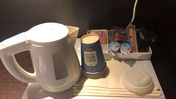 A coffee maker, a blue container labeled 'BOVEZ', a white cup, and a tray with food items and a power cord.