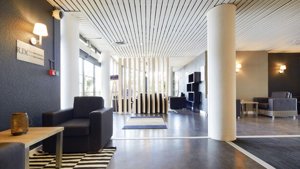 A modern lobby with a checkered floor, a reception desk, and seating areas.