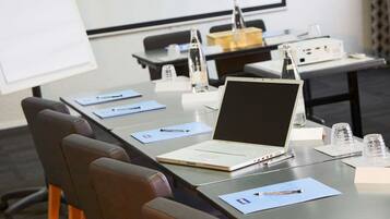 A conference room with a laptop, documents, and a projector screen.