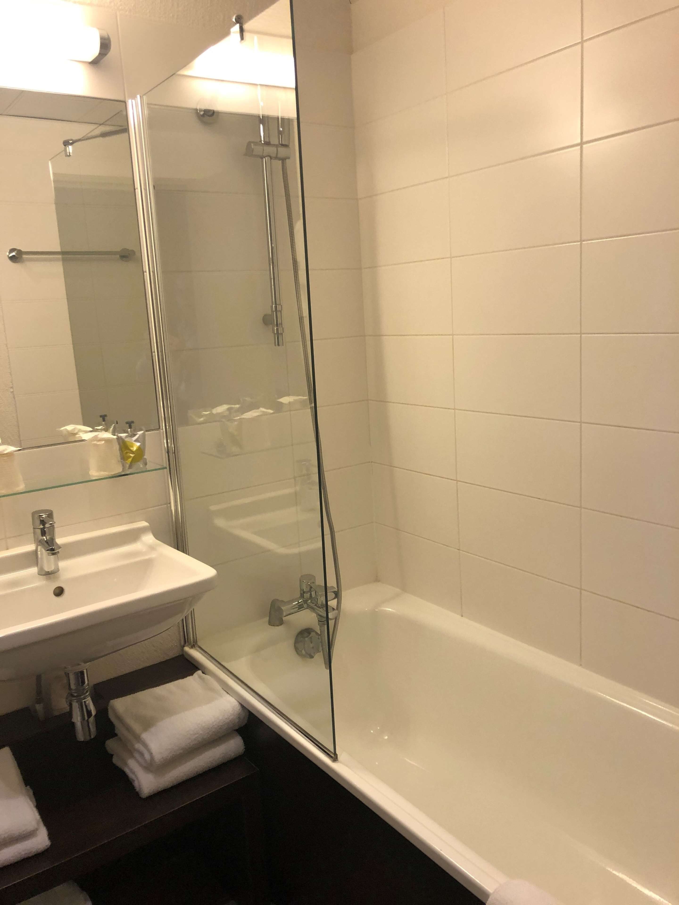 Un baño con ducha de vidrio, lavabo blanco y bañera.
