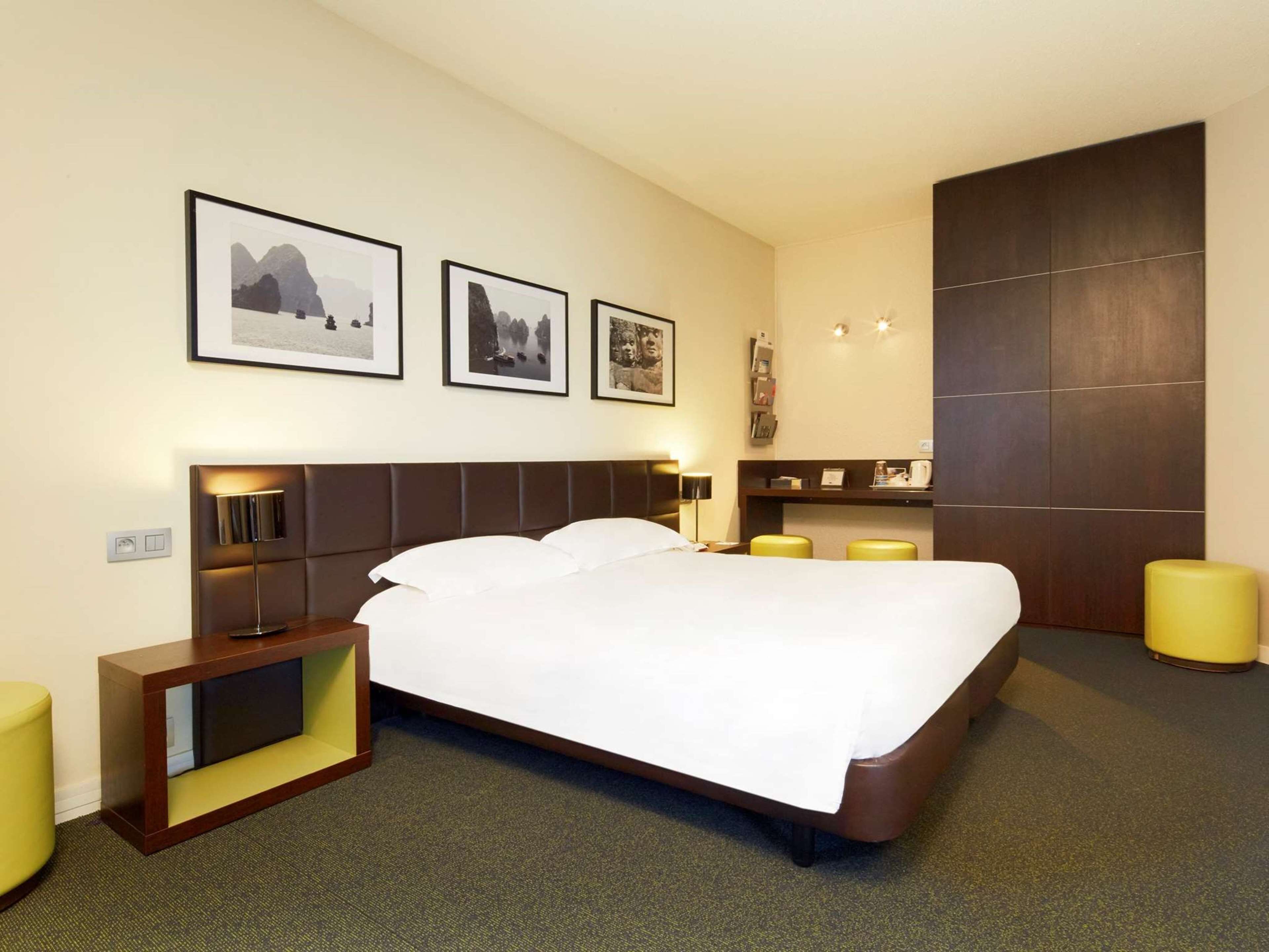 Une chambre d’hôtel moderne dotée d’un grand lit, de tables de chevet, d’un bureau et d’un coin salon.