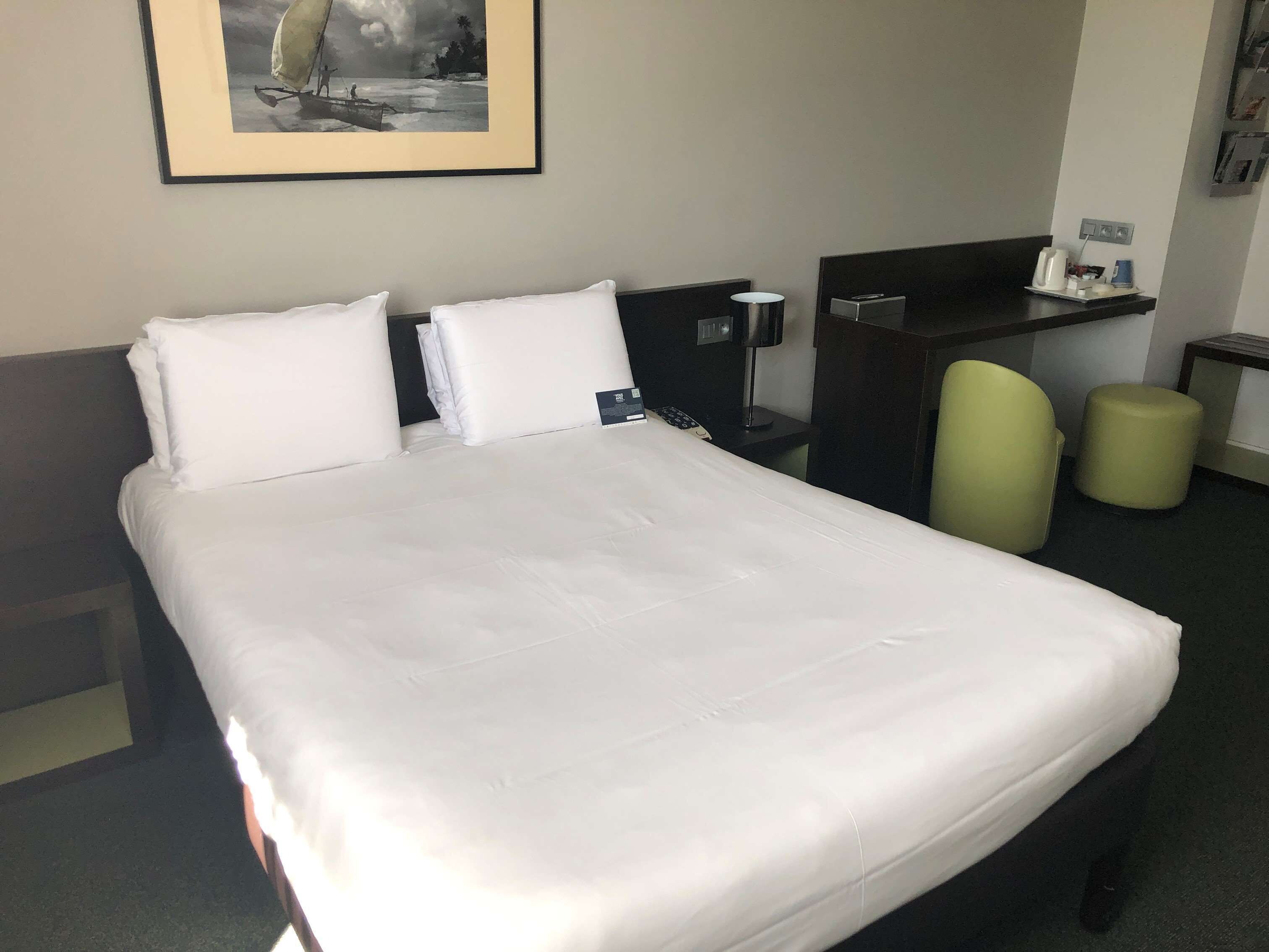 Habitación de hotel con una cama grande, un escritorio, una silla y un taburete pequeño.