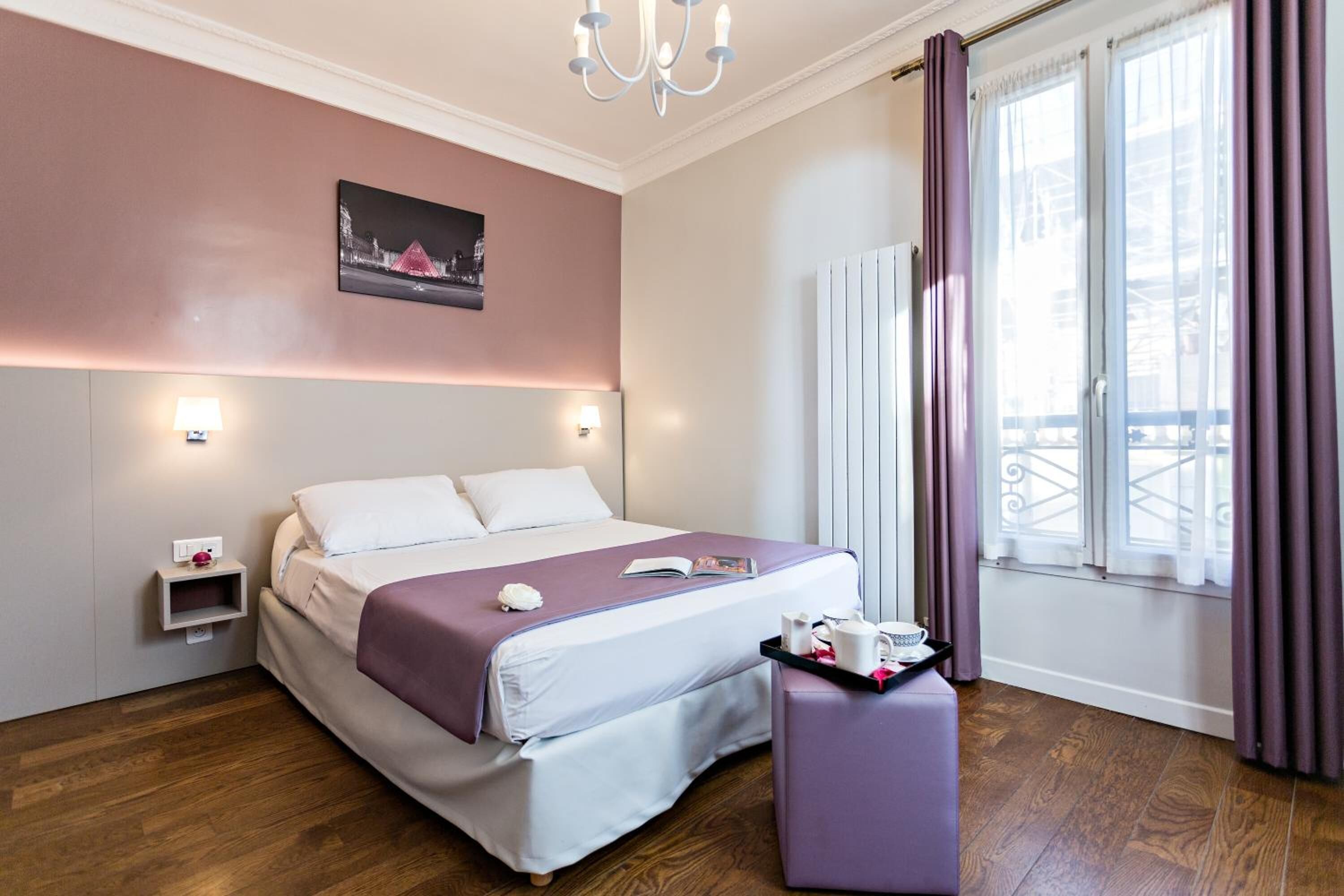 Ein modernes Hotelzimmer mit einem großen Bett, Nachttischen, einem Fenster mit Vorhängen und Blick nach draußen.