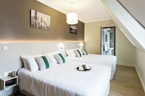 Habitación de hotel con dos camas, una mesita de noche con teléfono, una bandeja con t é y un cuadro en la pared.