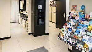 Rebuda d'hotel amb una taquilla d'informació, un televisor penjat a la paret i una presentació de fulletons.