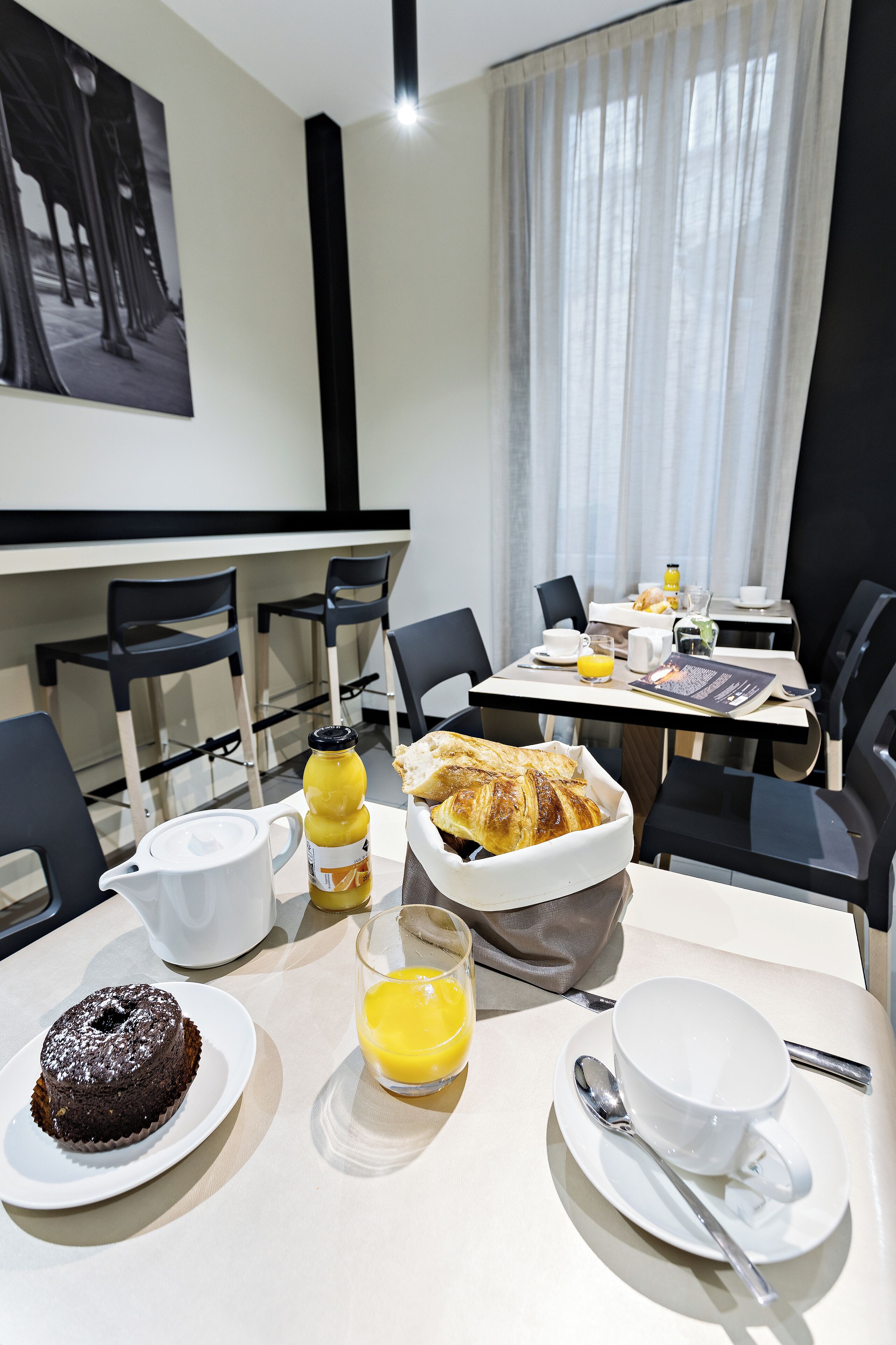 Un desayuno con cruasanes, pastel de chocolate y jugo de naranja sobre una mesa.