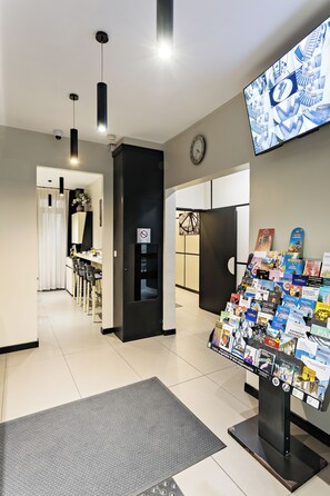 Un interior moderno con una mesa de recepción, un reloj en la pared y una exhibición de folletos.