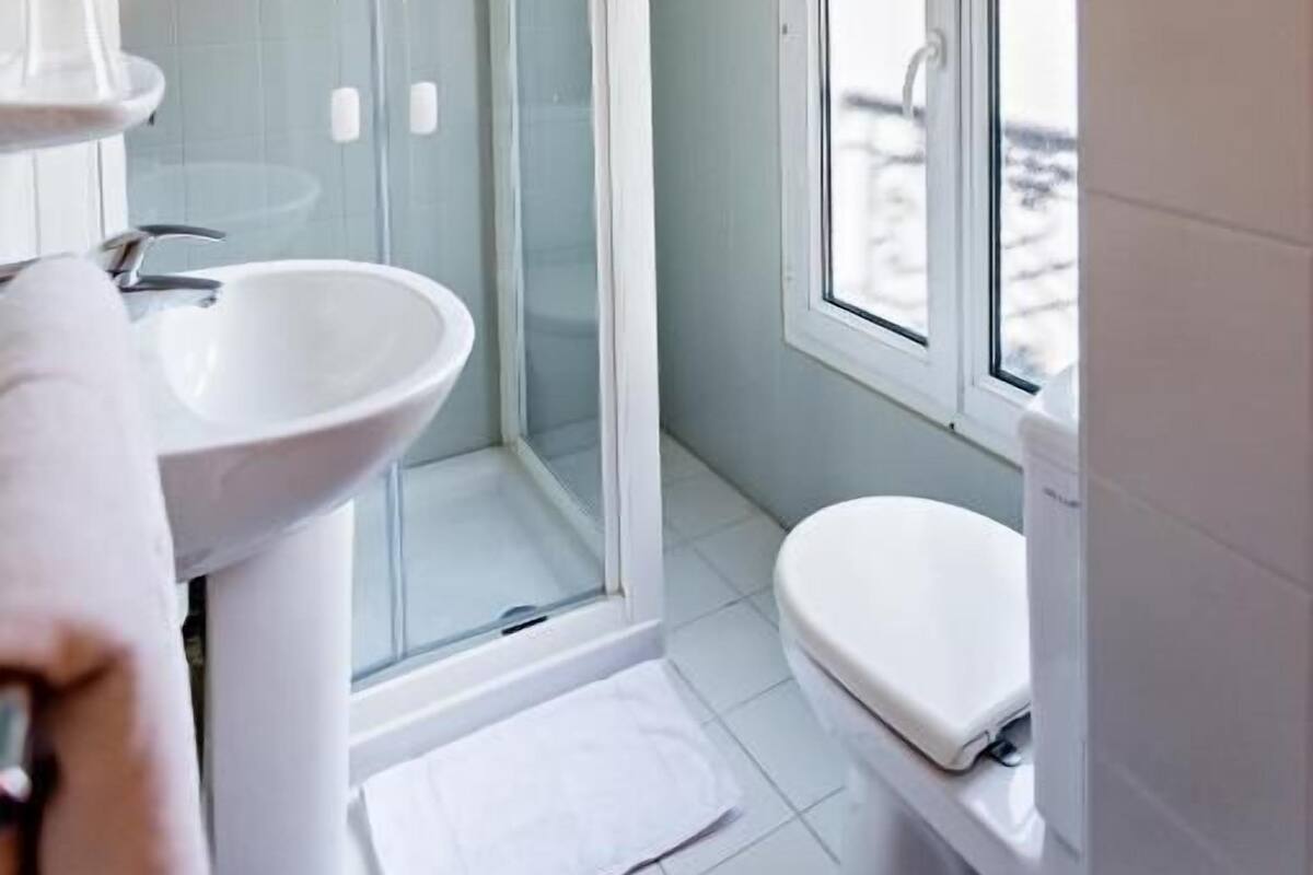 Un baño moderno con ducha de vidrio, un lavamanos blanco y un inodoro.