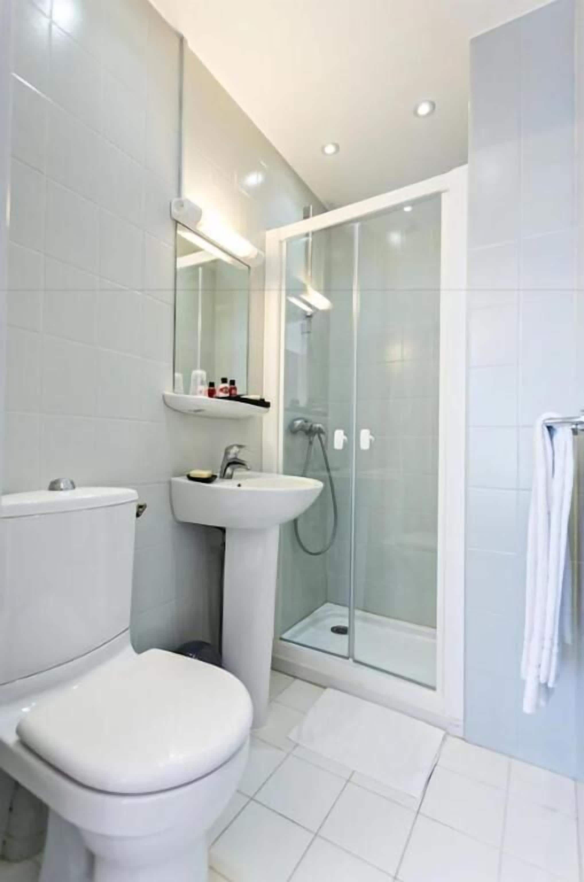 A modern bathroom with a toilet, sink, and glass-enclosed shower.