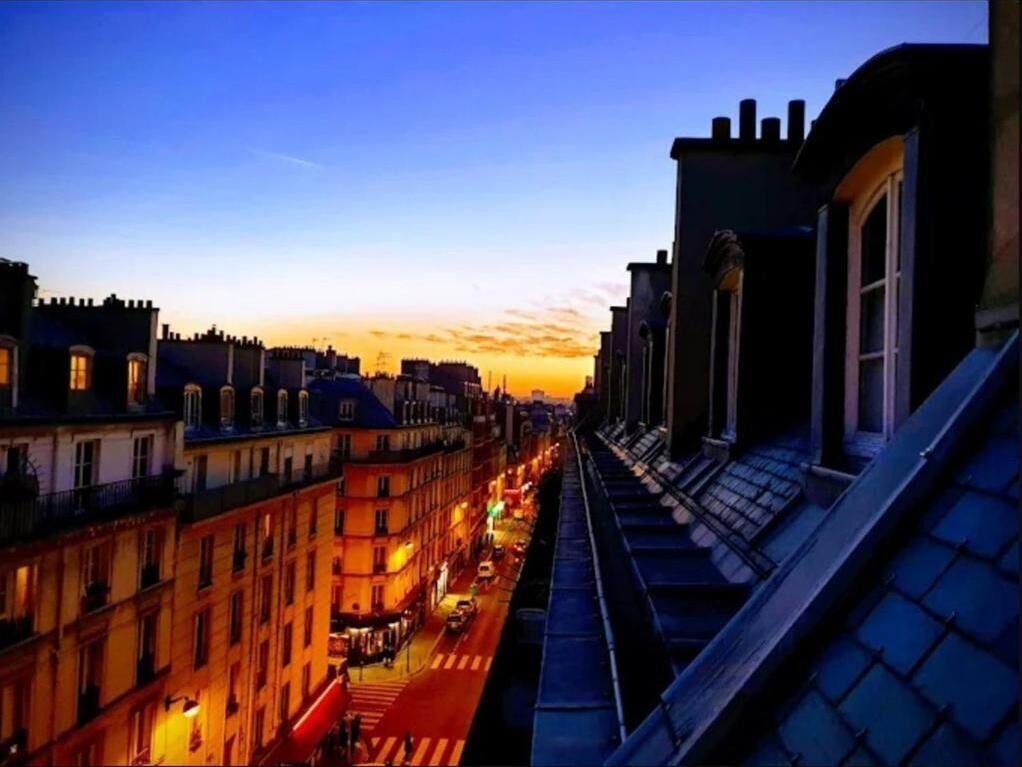 Un paisaje urbano nocturno con edificios a lo largo de una calle, un paso de peatones y un puente.