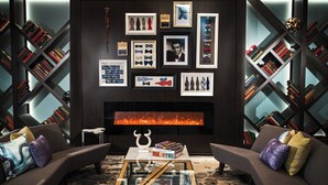 A modern living room with a fireplace, bookshelves, and a glass coffee table. - The Lindy Renaissance Charleston Hotel (Charleston)