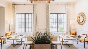 A modern living room with a large window, a central plant, and a chandelier. - The Lindy Renaissance Charleston Hotel (Charleston)