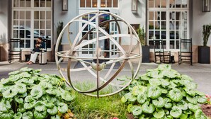A hotel entrance with a large metal sculpture, a covered entrance area, and a flag. - The Lindy Renaissance Charleston Hotel (Charleston)
