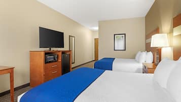 Een hotelkamer met twee bedden, een televisie, een magnetron en een bureau.