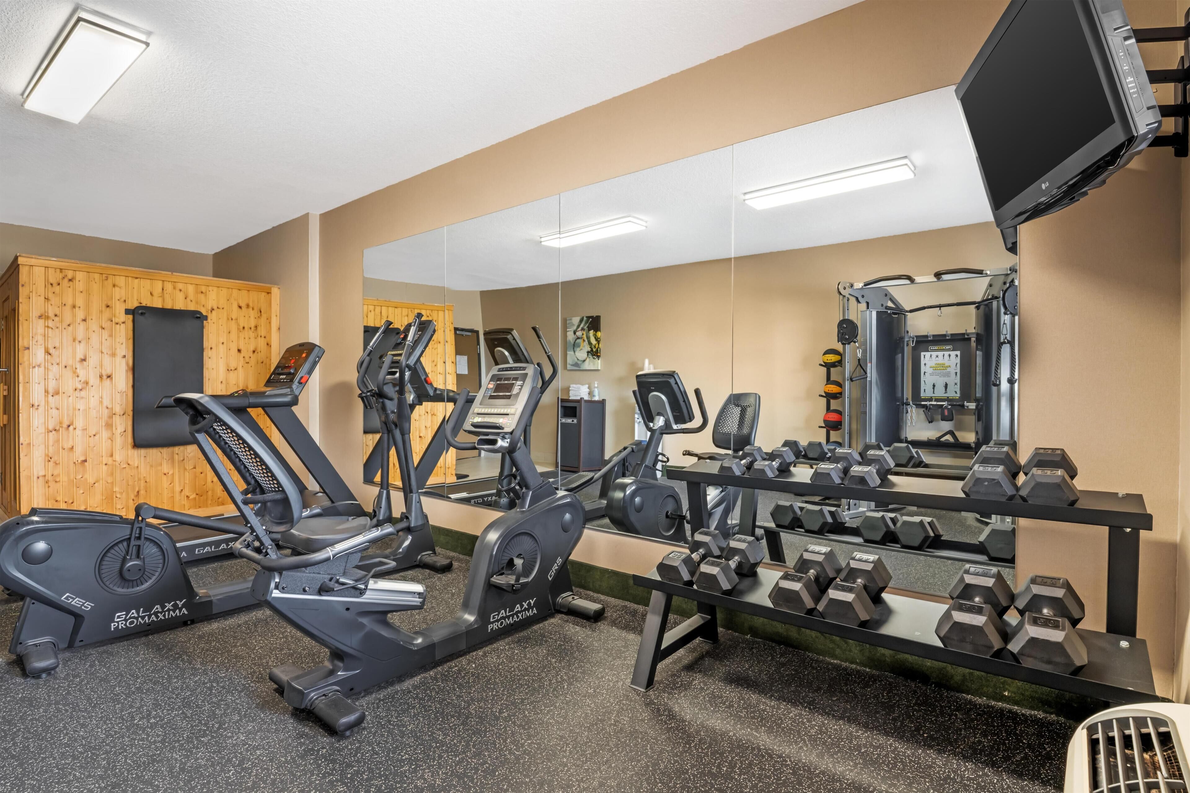 A gym with stationary bikes, treadmills, and dumbbells.