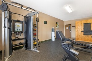 A gym with exercise equipment, a water dispenser, and a wooden wall. - Best Western Big Spring Lodge (Neosho)
