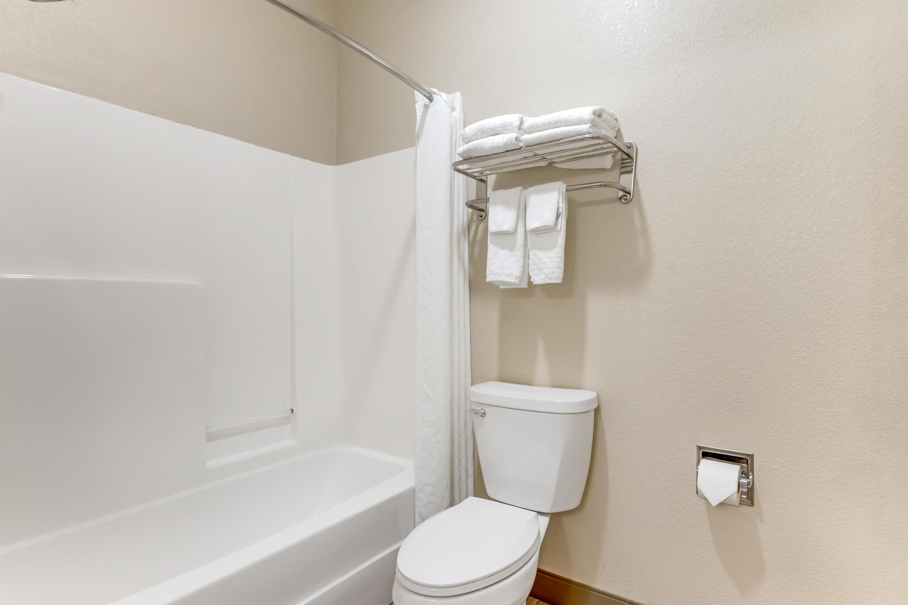 Ein Badezimmer mit einer weißen Badewanne, Toilette und Handtuchhalterung.