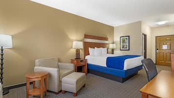 Een hotelkamer met een bed, een stoel, een klein tafeltje, een nachtkastje en een lamp.