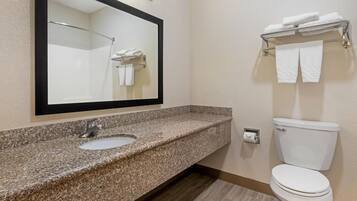 A bathroom with a granite countertop sink, a mirror, a toilet, and a towel rack.
