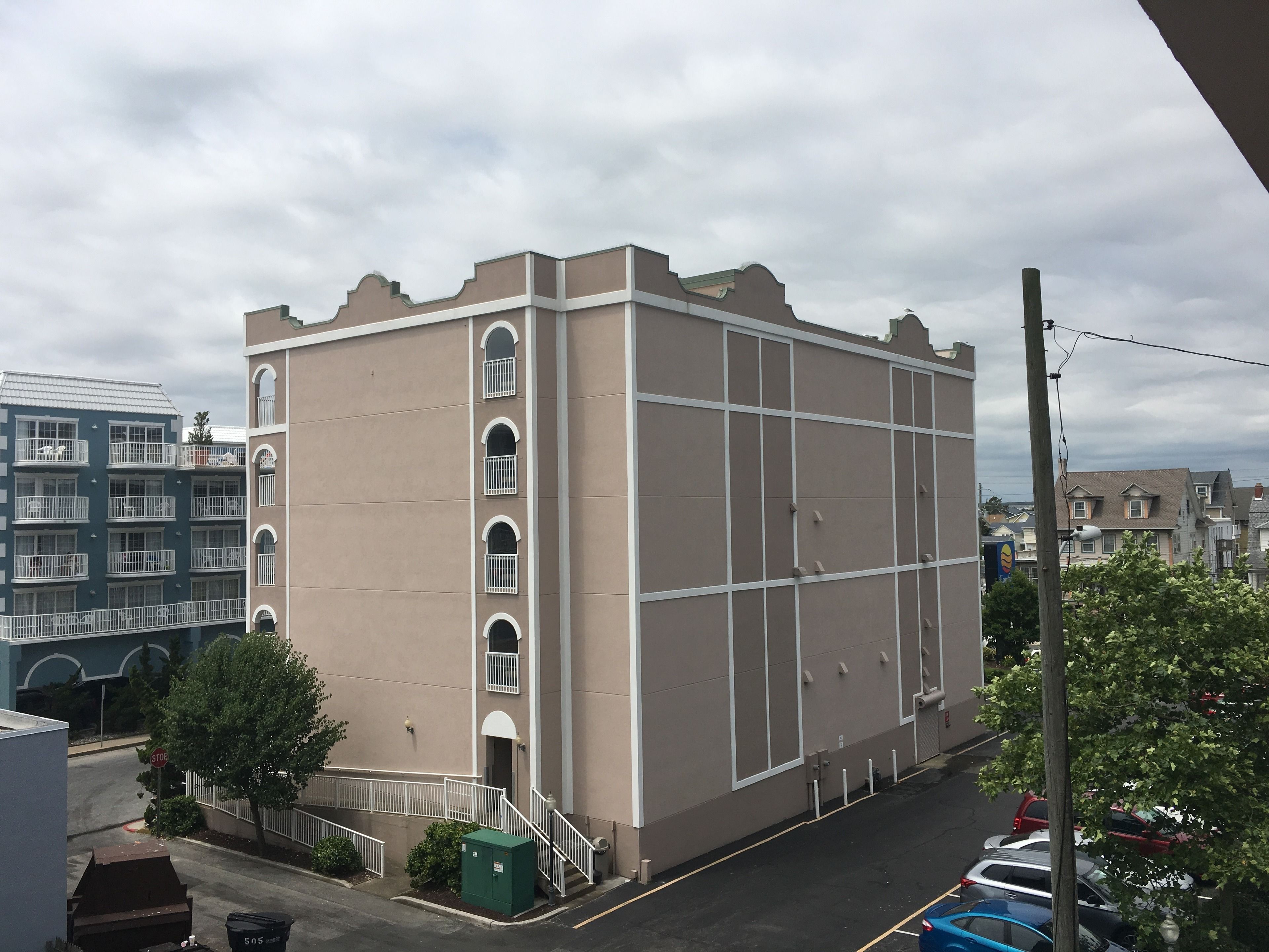 A multi-story building with a beige facade, white window frames, and a flat roof.