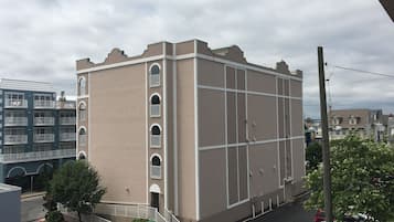 A multi-story building with a beige facade, white window frames, and a flat roof.