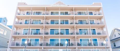 Un hotel de varios pisos con balcones, techo plano y fachada blanca.