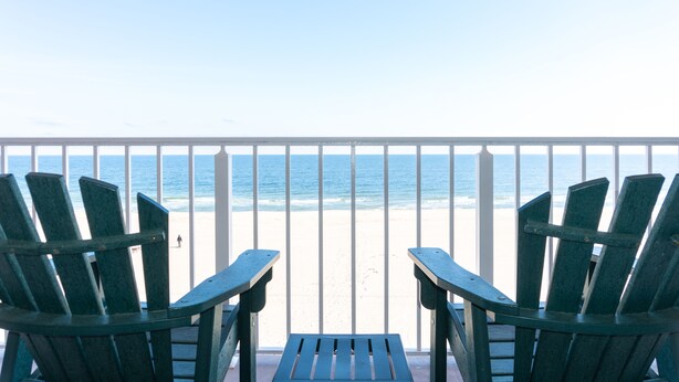 A balcony with two green Adirondack chairs facing a beach. - Comfort Inn Ocean City Boardwalk (Ocean City)