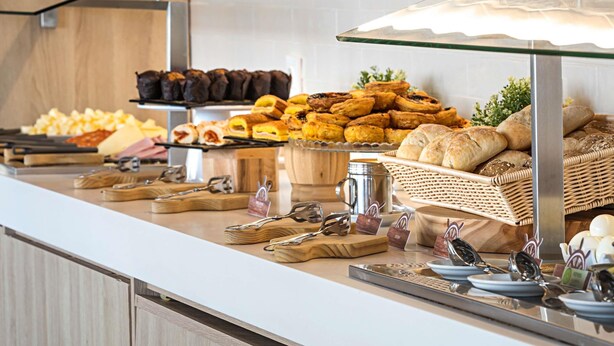 Un buffet proposant une variété de plats, notamment des pâtisseries, du pain et un coin café.