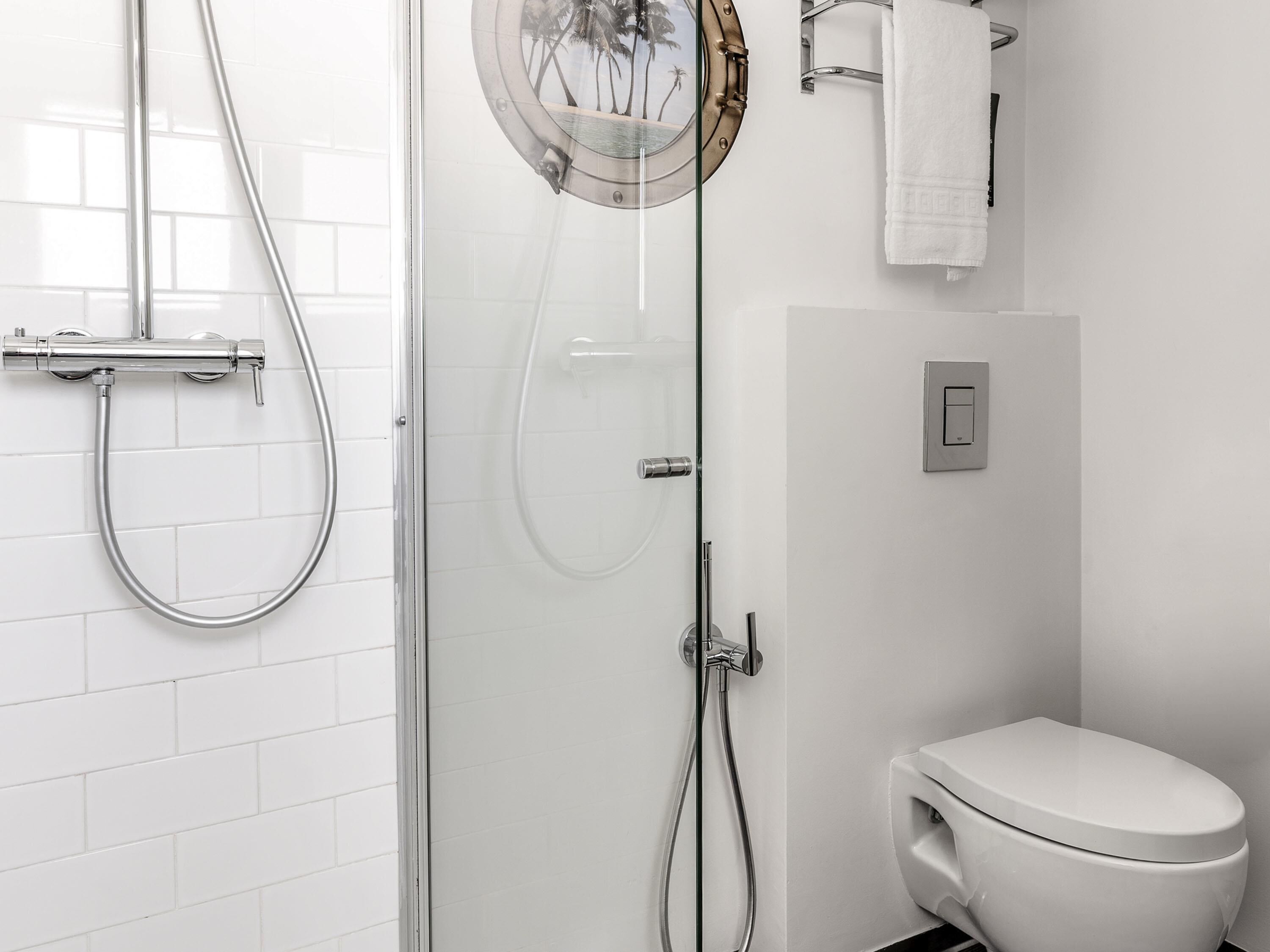 A modern bathroom with a glass shower enclosure, a toilet, and a towel rack.