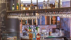 Un espace bar avec un assortiment de bouteilles d’alcool, de verres et un tableau noir sur lequel on a écrit.