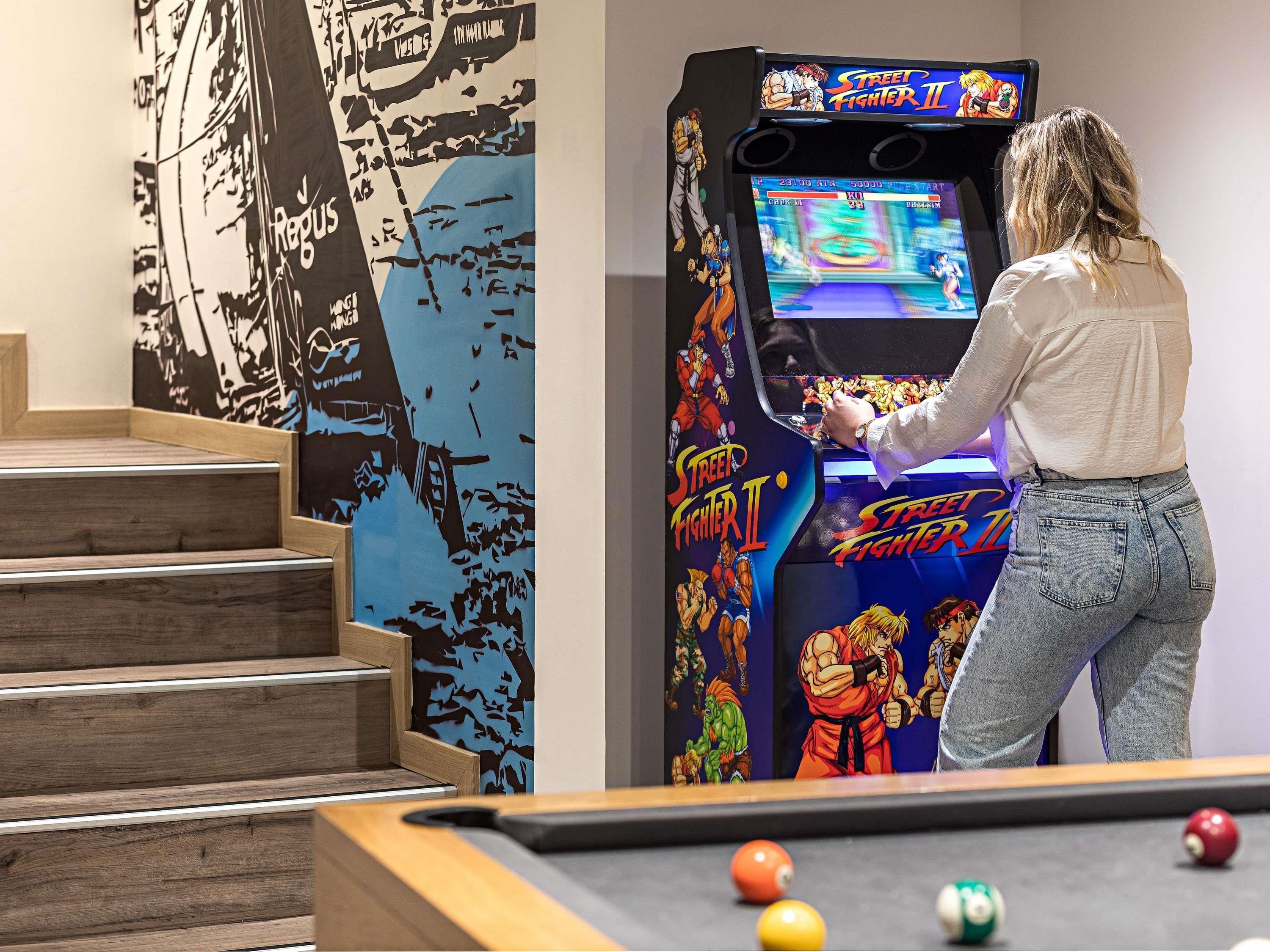Eine Person spielt Street Fighter II in einer Spielhalle.