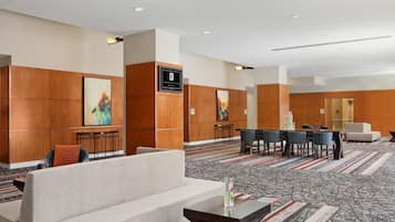 Um saguão moderno de hotel com área de estar, balcão de recepção e obras de arte nas paredes.