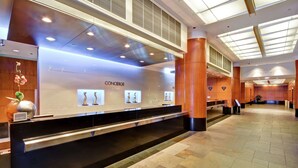 A hotel reception area with a black reception desk, a concierge service sign, and a tiled floor. - Embassy Suites by Hilton Chicago Downtown Magnificent Mile (Chicago)