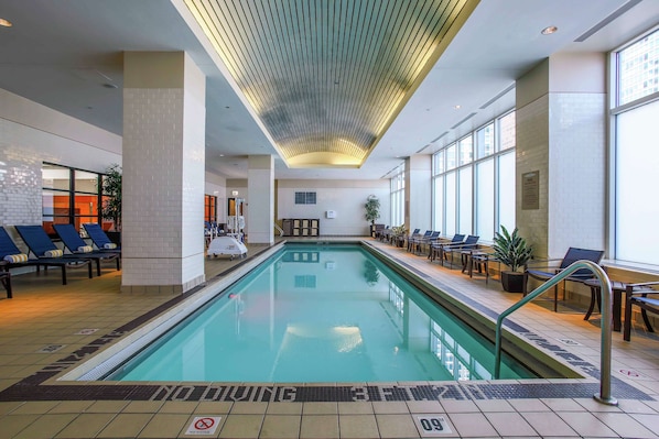 Una piscina interior con sillas de descanso y un cartel que prohíbe el clavado.