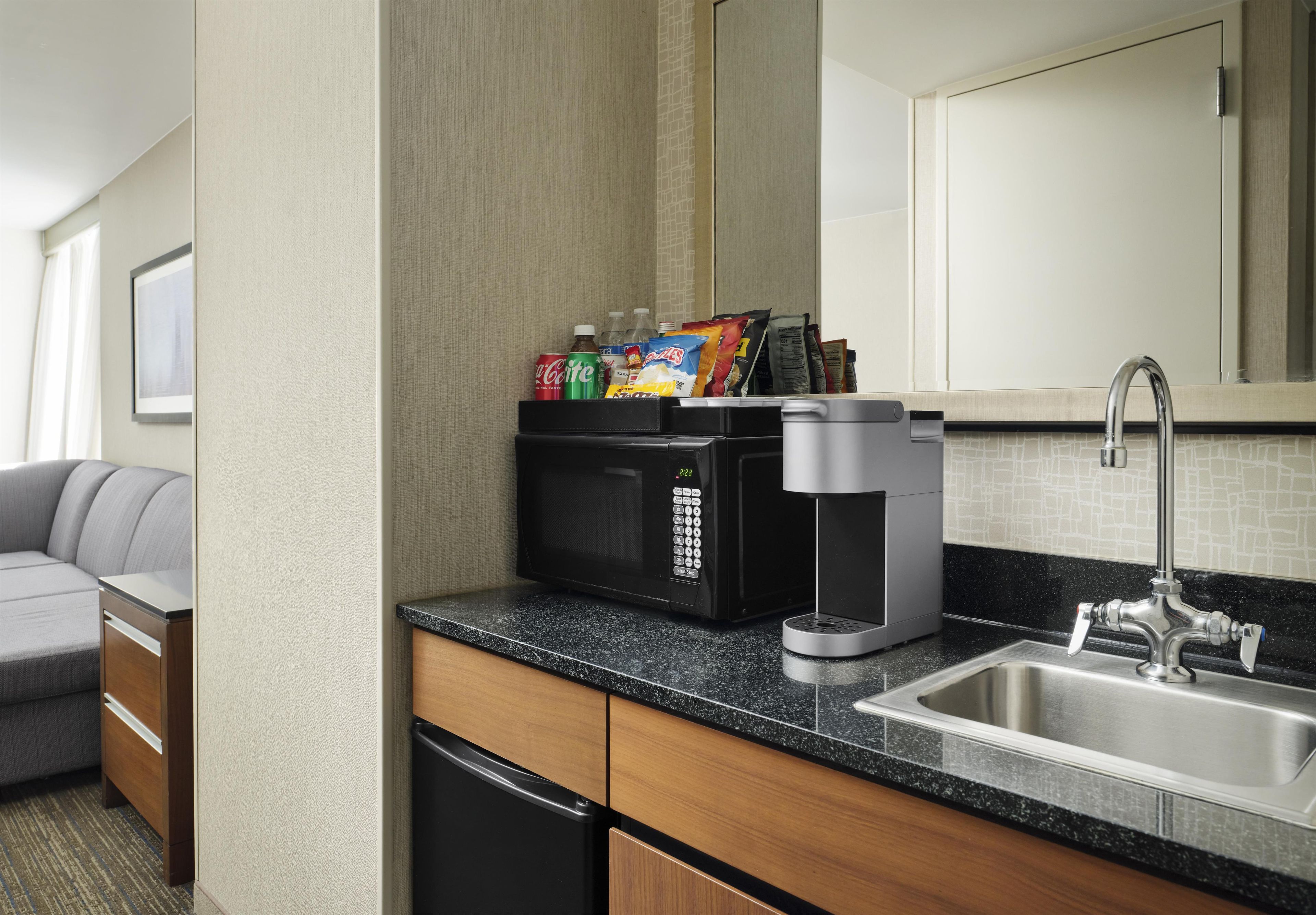 A compact kitchenette with a microwave, coffee maker, and a small refrigerator.